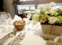 パーティ開催前の会場の様子、花が飾られたテーブルに食器が置かれています。パーティに参加したくなります。